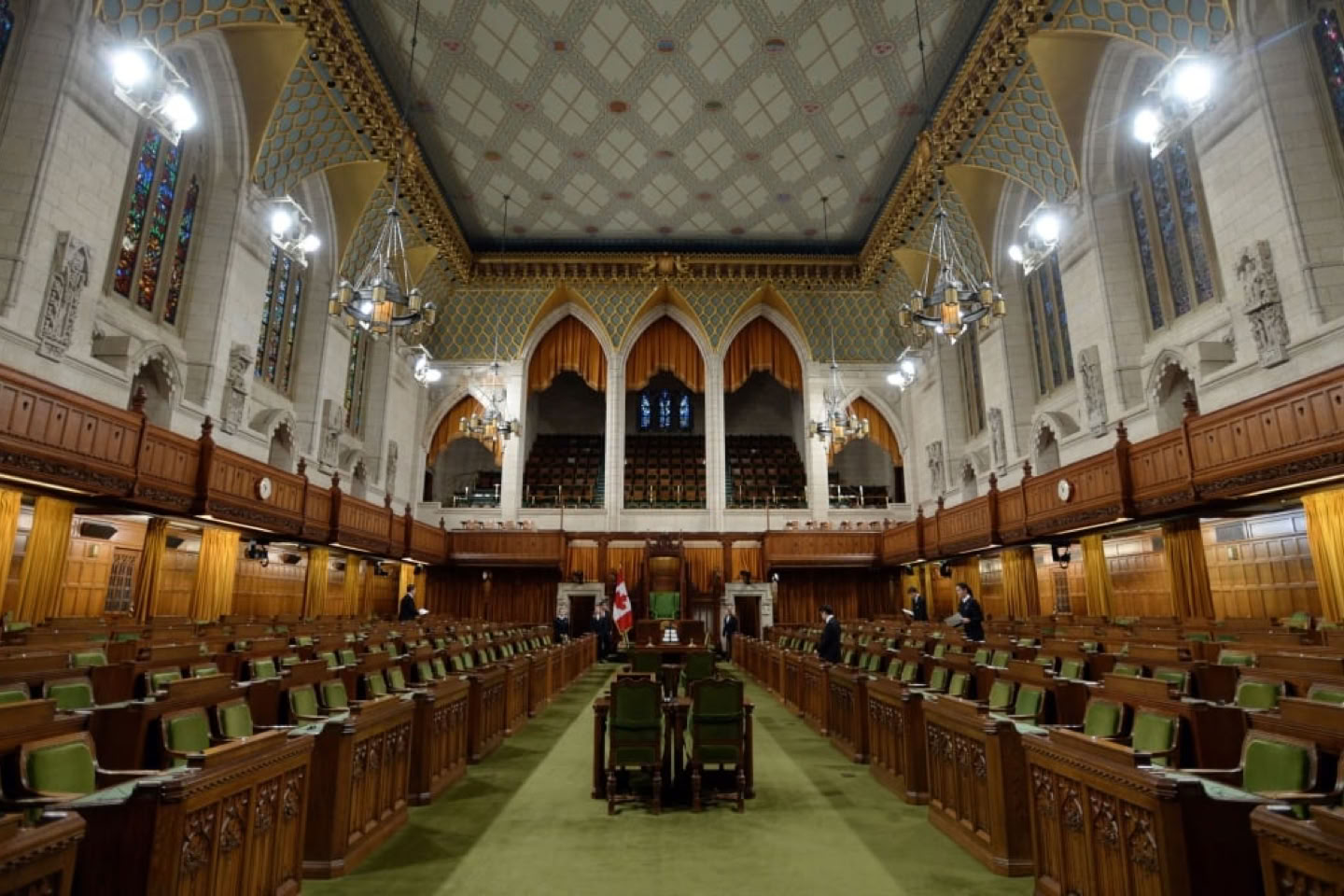 A large, ornate hall with high ceilings, wooden paneling, and rows of green seats facing a central area.