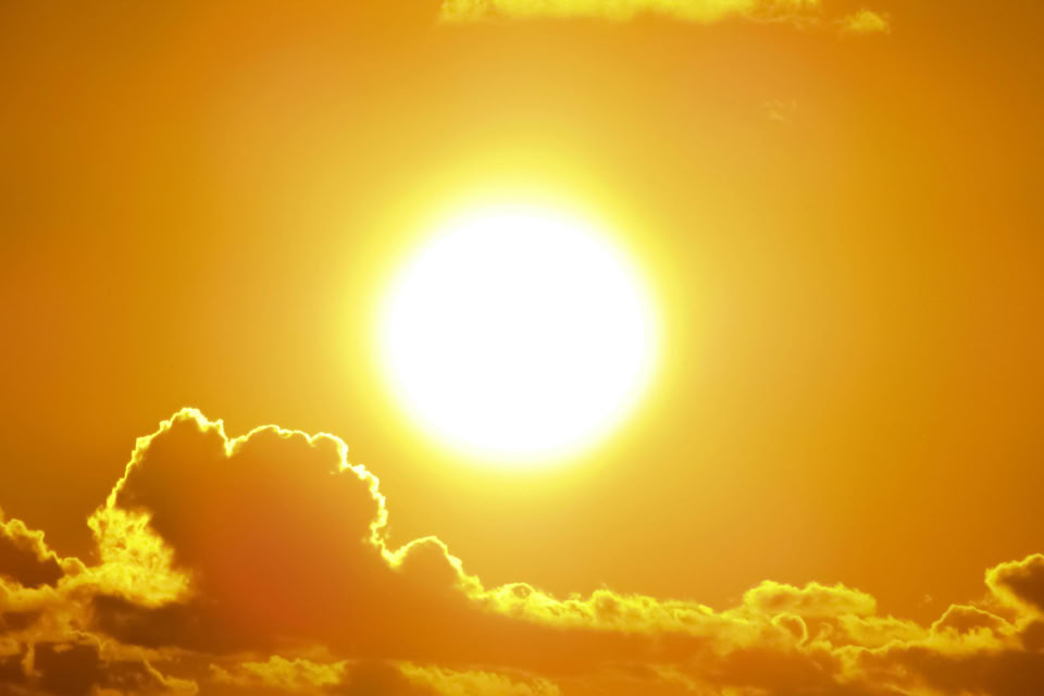 Bright sun in a yellow-orange sky with clouds at the bottom.