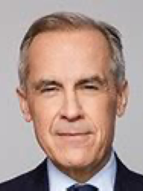 Man with short gray hair wearing a dark suit and tie against a plain background.